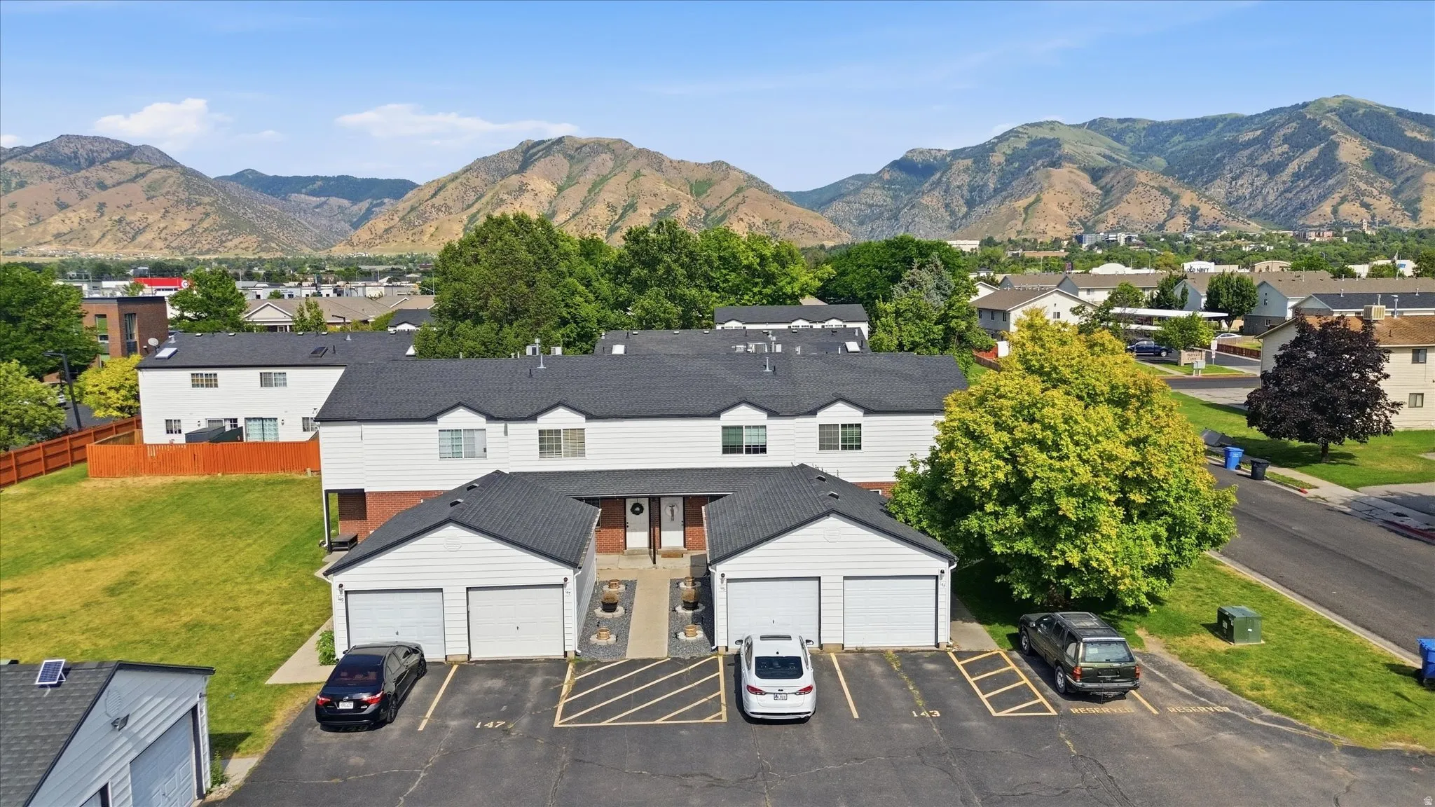 Multi-level residential building featuring white siding and dark roofs, with attached garage spaces