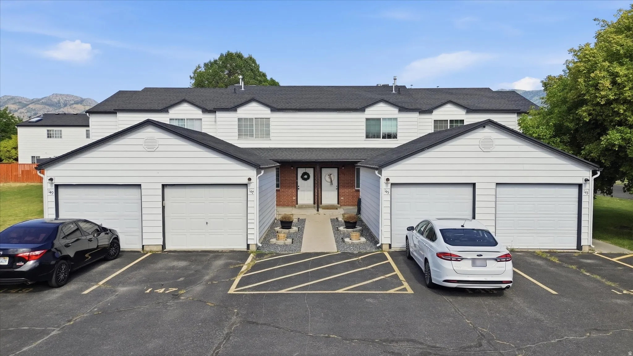 Multi-unit residential structure featuring white horizontal siding and a dark shingle roof