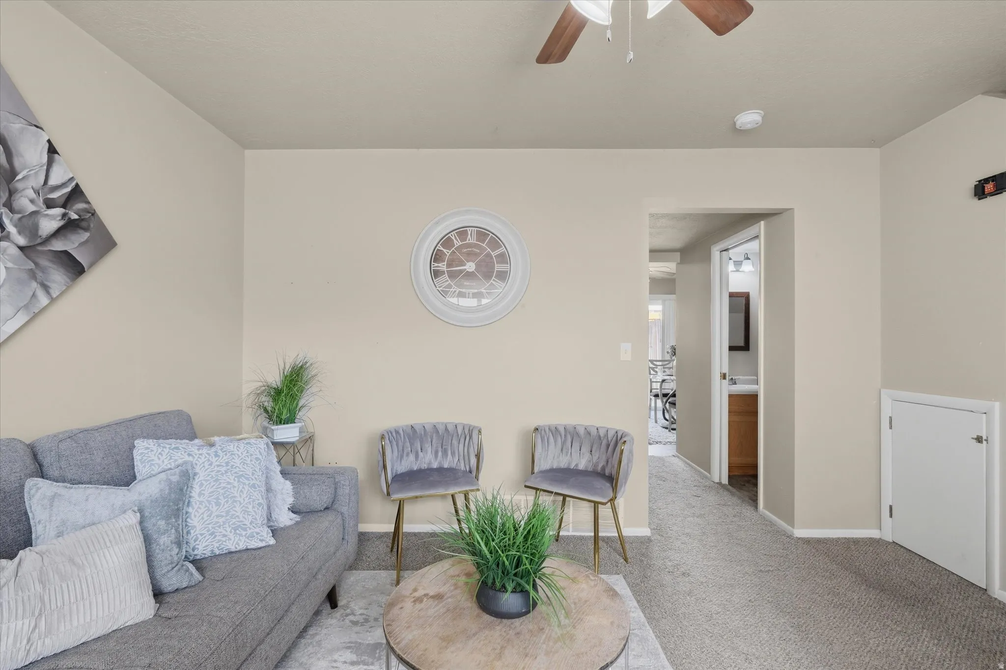 Neutral-toned walls complement the textured gray carpeting throughout this living space