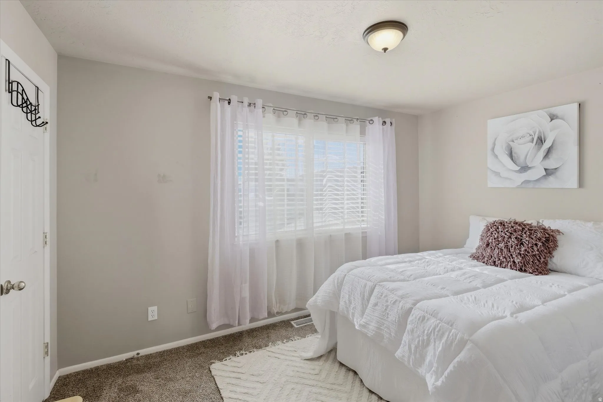 Light-filled room featuring a ceiling-mounted light fixture, neutral wall paint, and window blinds with sheer curtains