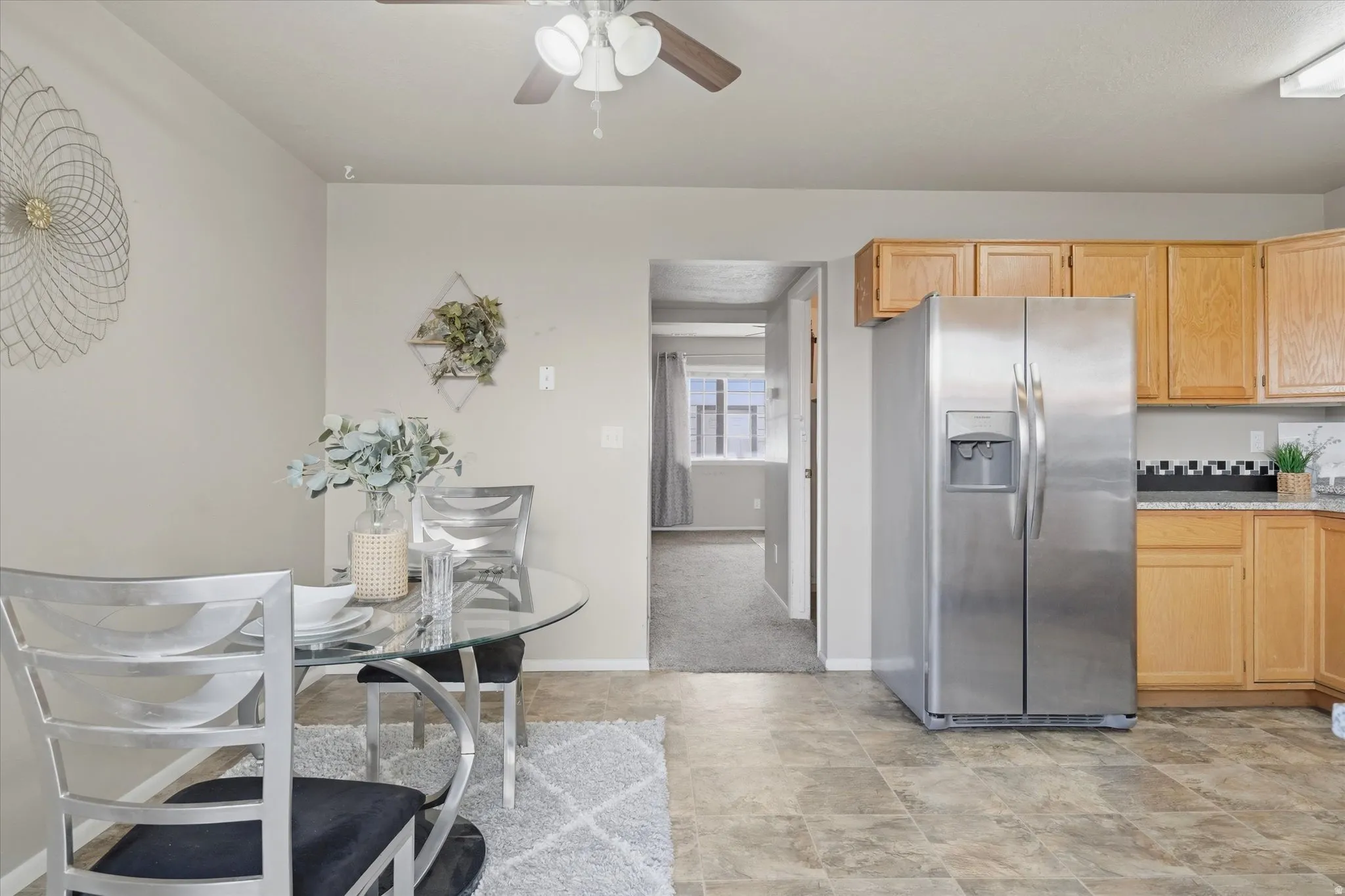 Kitchen and dining area featuring warm-toned cabinetry, a stainless steel side-by-side refrigerator, and patterned vinyl flooring
