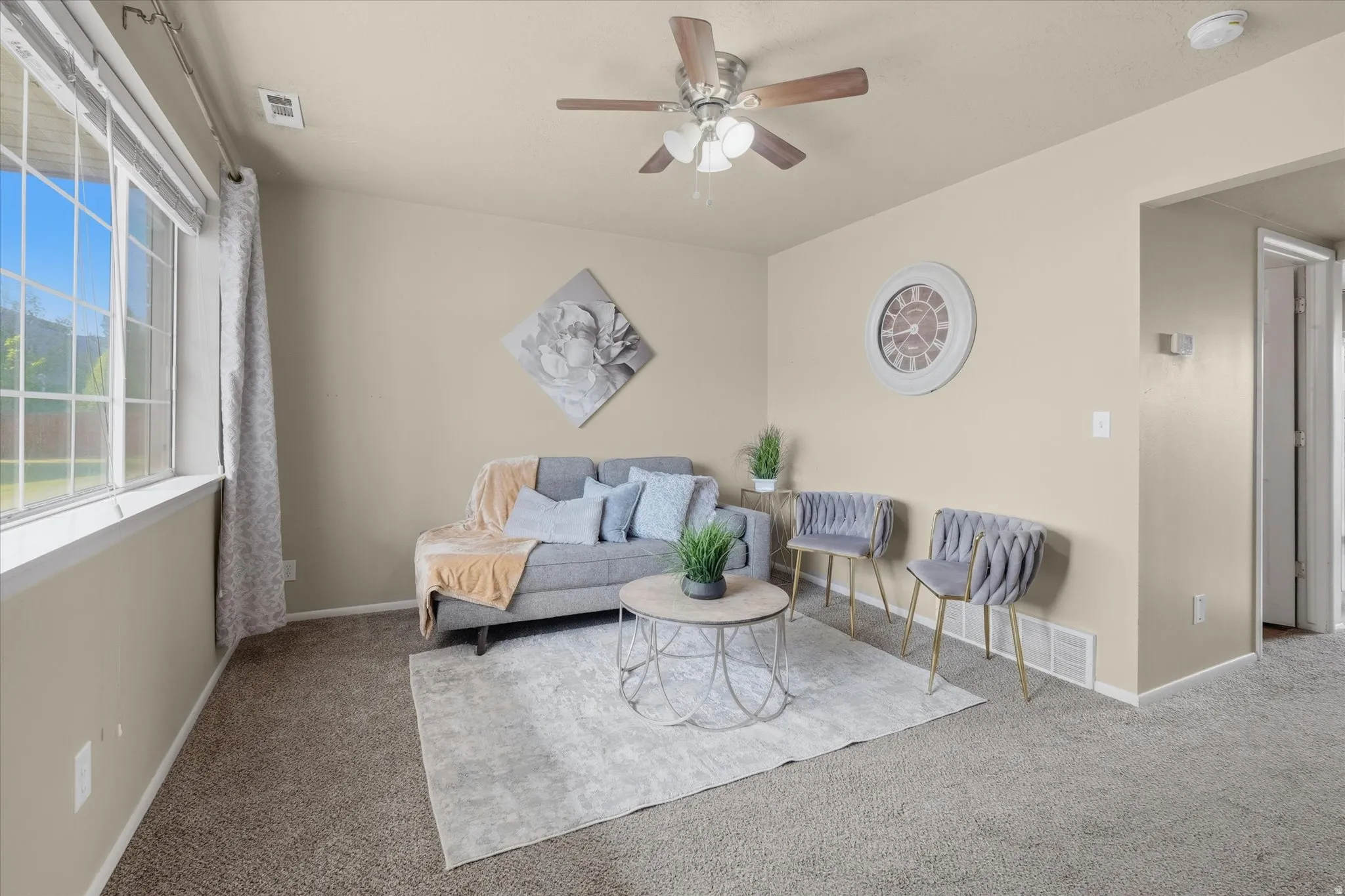 Carpeted living space with a large multi-pane window, vaulted ceiling, and a ceiling fan with integrated lighting