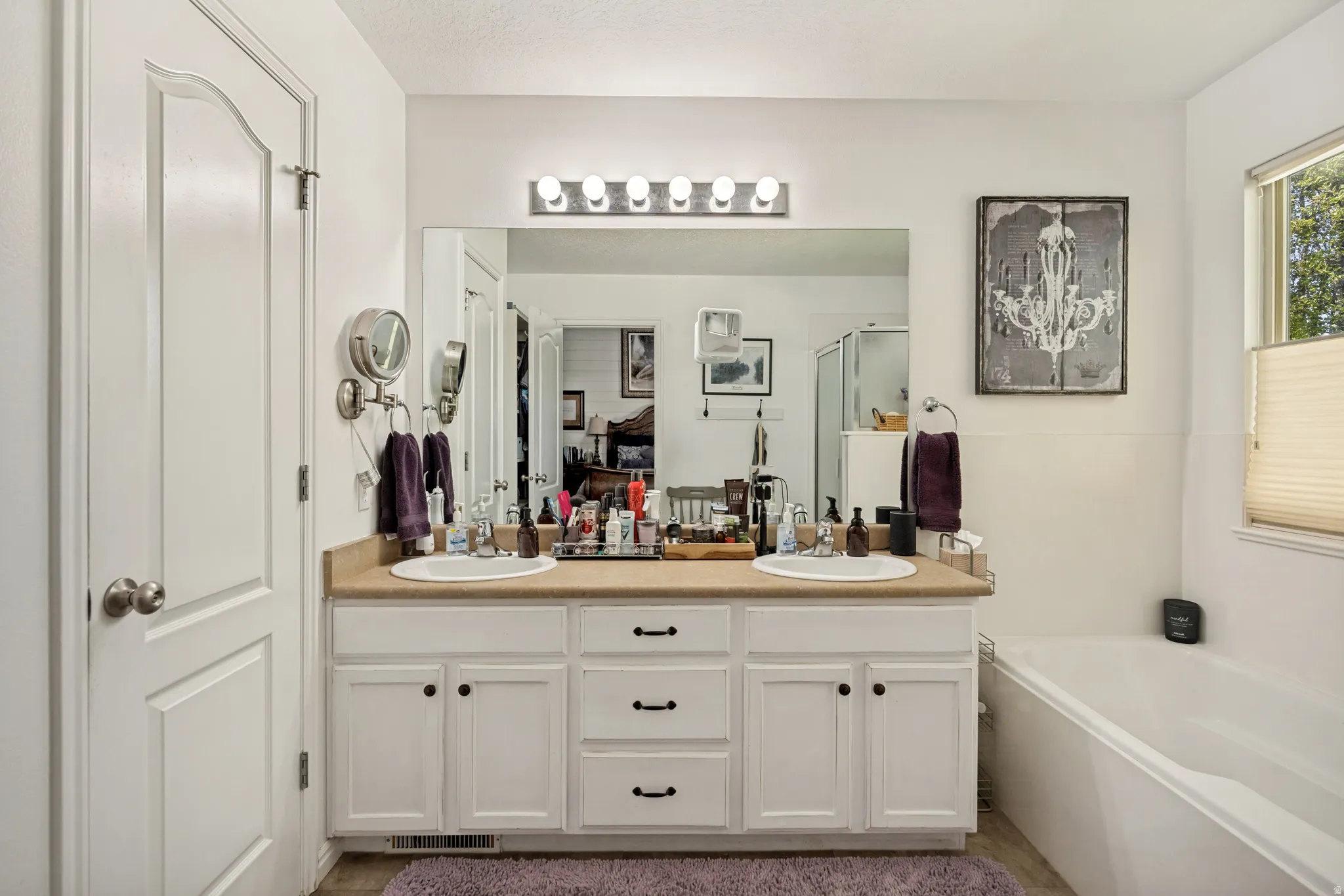 Double vanity with ample cabinet storage, large mirror, and a wall-mounted light fixture