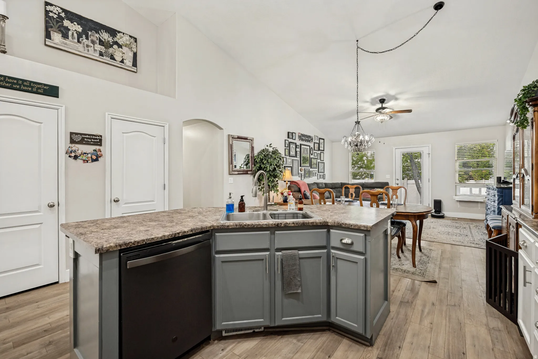 Spacious kitchen island with a built-in sink and dishwasher, featuring gray cabinetry and a stone-finish countertop