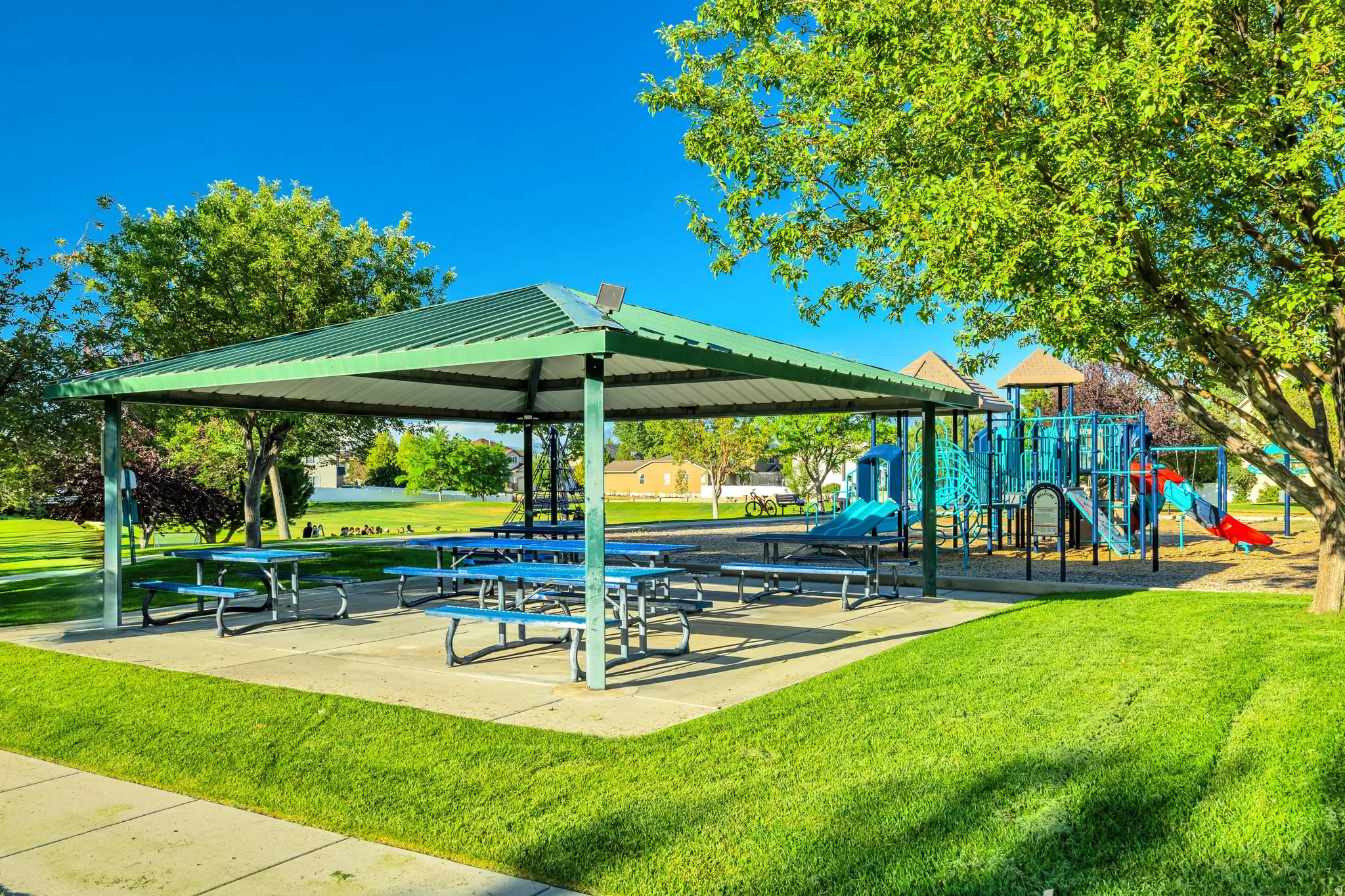 Covered picnic area with multiple tables, adjacent to a playground structure
