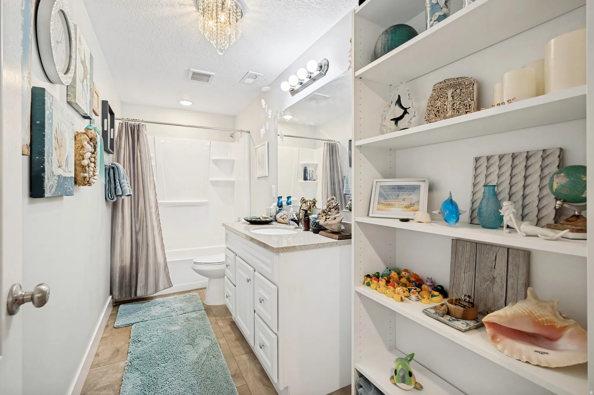 Full bathroom featuring a white vanity with a light-toned countertop, a shower-tub combination, and built-in shelving