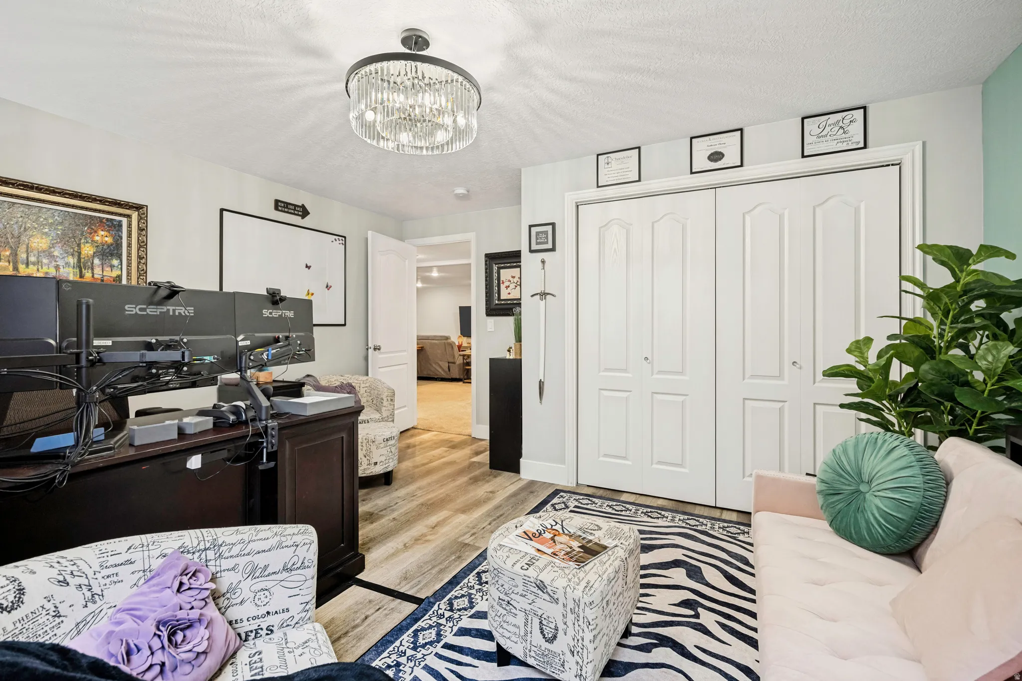 Interior room featuring wood-finish flooring, a contemporary chandelier, light-toned walls, and white bi-fold closet doors