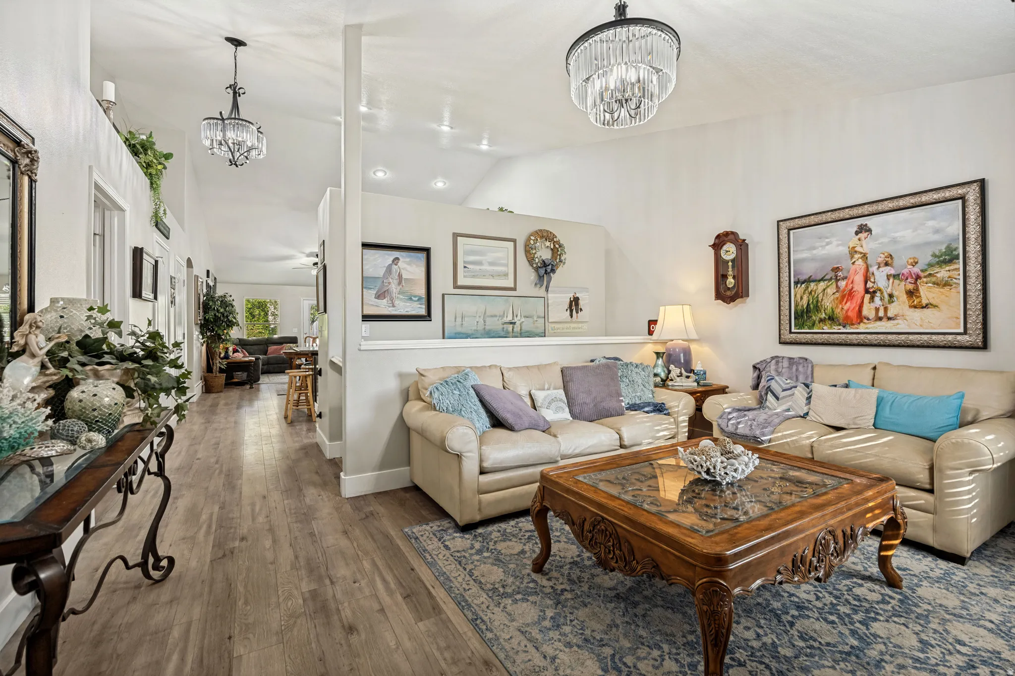 Spacious living area featuring vaulted ceilings, wood-finish flooring, recessed lighting, and elegant chandelier fixtures
