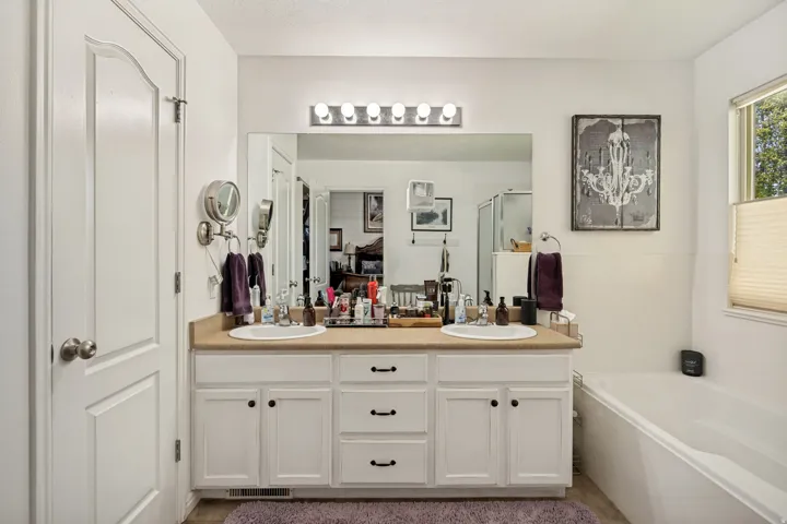 Double vanity with ample cabinet storage, large mirror, and a wall-mounted light fixture