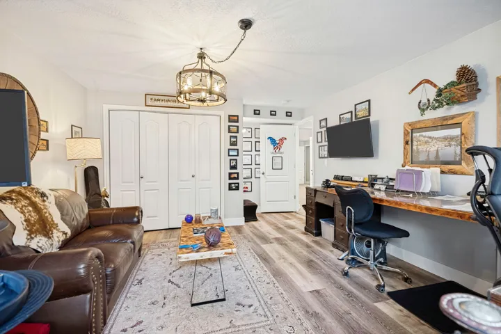 Spacious room featuring wood-finish flooring, a built-in wall-mounted desk, and a decorative ceiling light fixture
