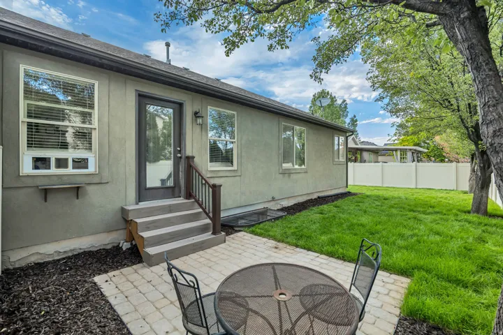 Outdoor patio featuring paver stones, a partial privacy fence, and a manicured lawn
