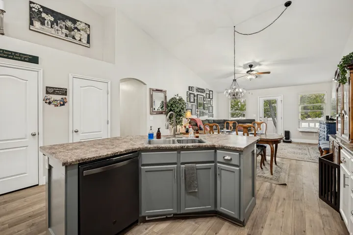 Spacious kitchen island with a built-in sink and dishwasher, featuring gray cabinetry and a stone-finish countertop