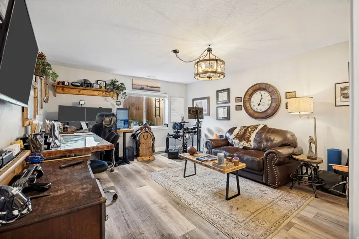 Spacious room featuring wood-finish flooring, light-toned walls, and a large window providing natural light