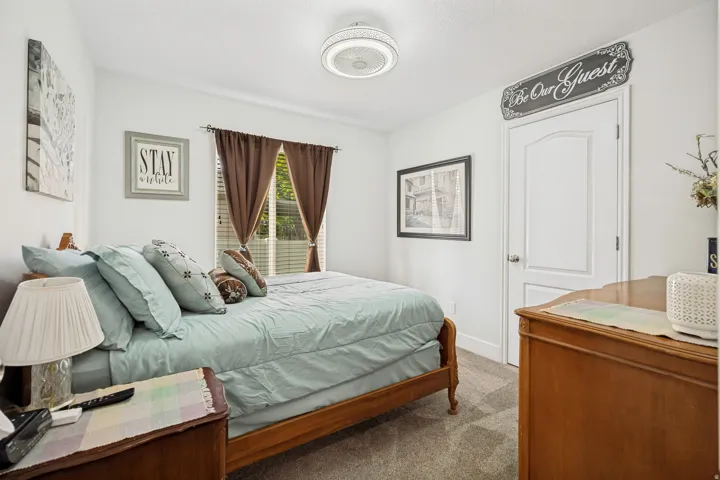 Bedroom featuring carpet flooring, a window with brown curtain panels, a built-in ceiling light fixture, and a white interior door