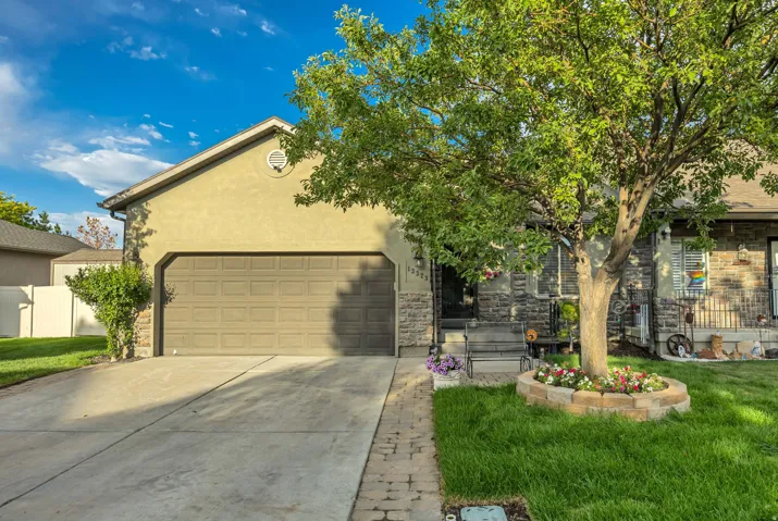 Exterior featuring a two-car garage, stone facade accents, and a stucco finish