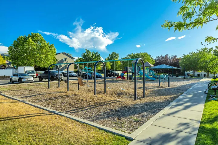 Community park featuring a swing set, playground equipment, and a covered picnic area