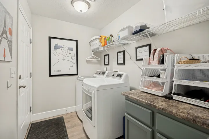 Dedicated laundry room featuring wood-finish flooring, a contemporary ceiling light fixture, and a built-in countertop with cabinet storage