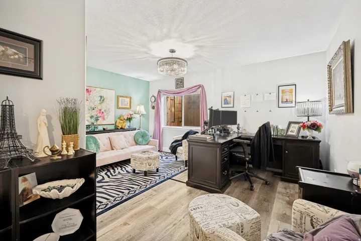 Interior space featuring wood-finish flooring, a textured ceiling, a chandelier light fixture, and a window with interior shutters