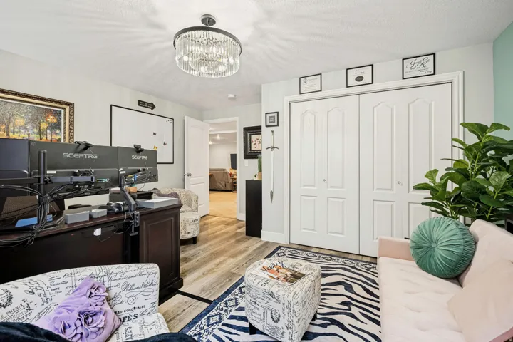 Interior room featuring wood-finish flooring, a contemporary chandelier, light-toned walls, and white bi-fold closet doors