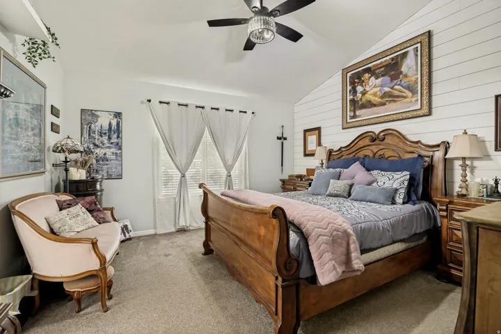 Vaulted ceiling bedroom featuring shiplap accent wall