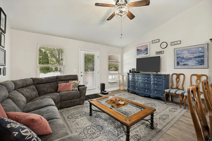 Spacious living area featuring vaulted ceilings, wood-finish flooring, and ample natural light from multiple windows