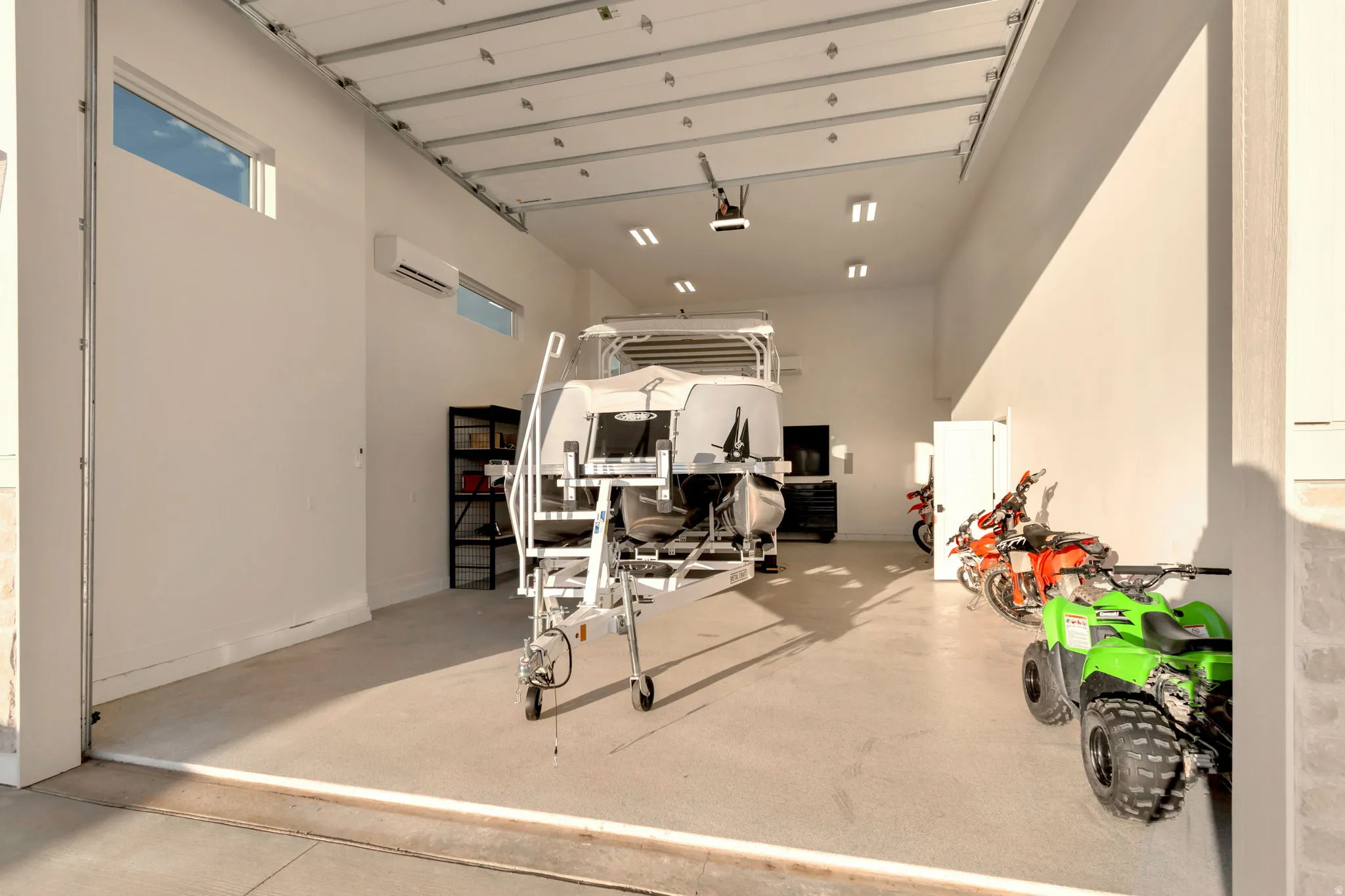 Expansive garage space with a large roll-up door, high ceilings, multiple recessed light fixtures, and a dedicated mini-split unit for climate control