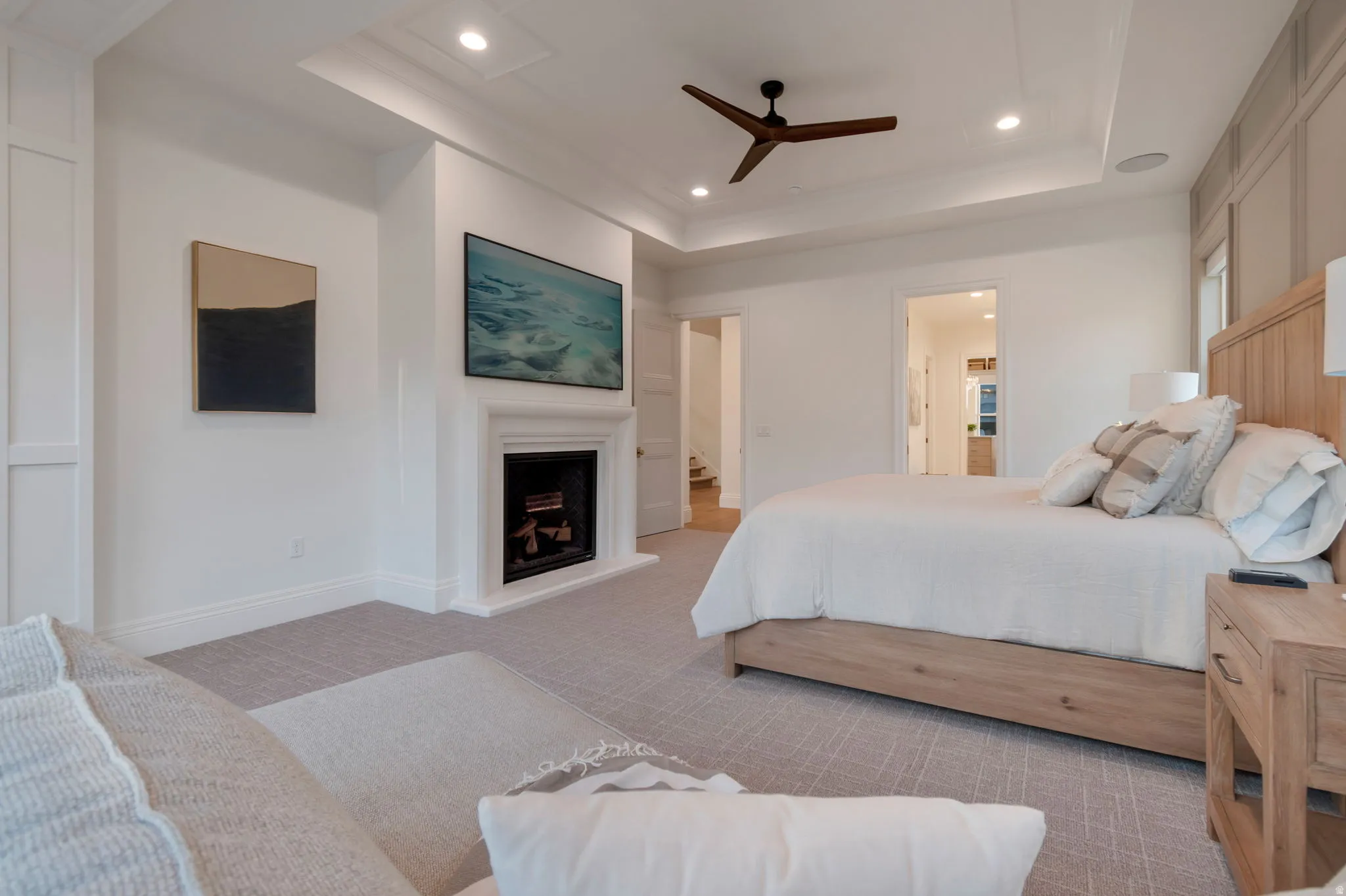 Recessed fireplace with hearth, wood-finish ceiling fan, tray ceiling, recessed lighting, and wall paneling