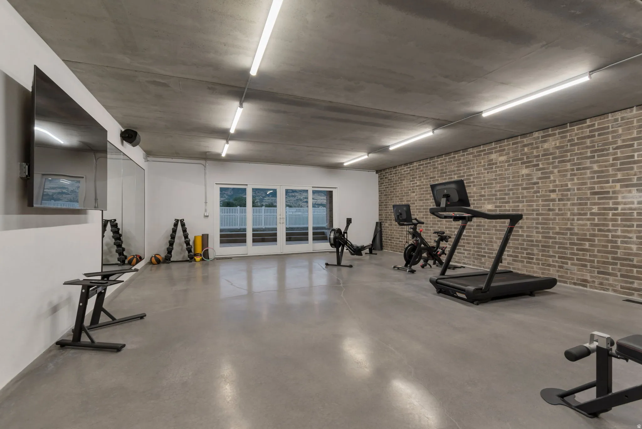 Gigantic home gym, with brick accent wall and sliding doors to the backyard