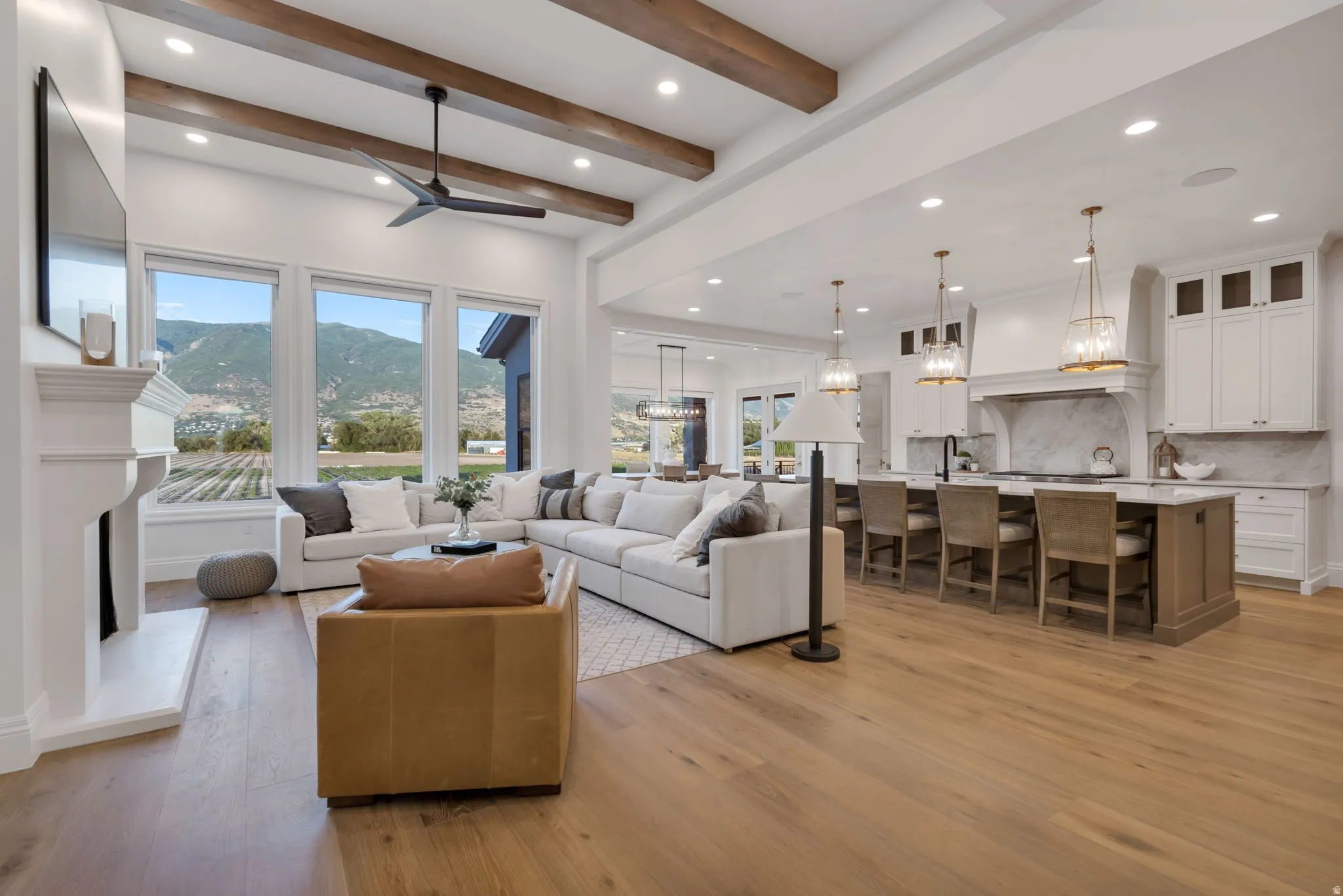 Expansive living area with high ceilings, exposed wood beams, and recessed lighting