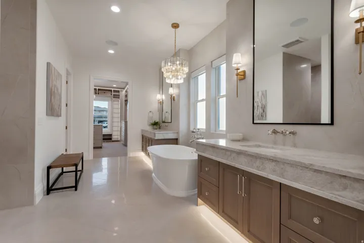 Spacious bathroom featuring a freestanding soaking tub, a large vanity with an integrated sink and stone countertop, and an ornate chandelier