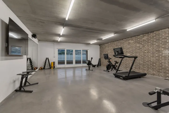 Gigantic home gym, with brick accent wall and sliding doors to the backyard