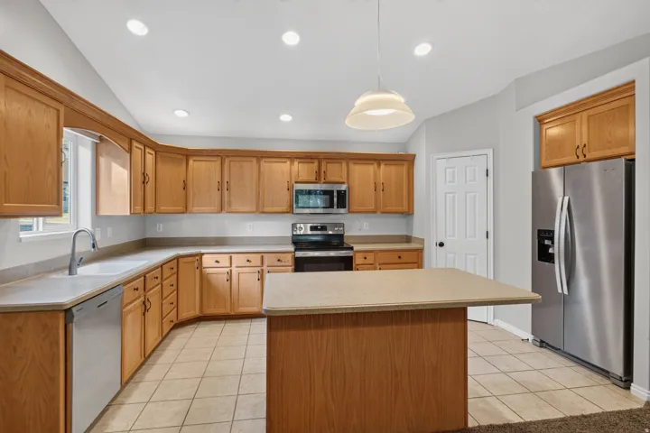 Kitchen featuring light wood cabinetry, light-colored countertops, and stainless steel appliances