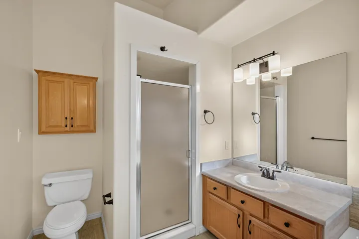 Bathroom vanity featuring a single sink with a chrome faucet, light-toned countertop, and wood-finish cabinetry
