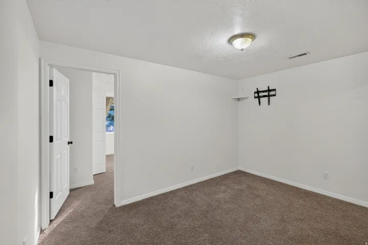 Carpeted interior room with white walls, white baseboards, and a white six-panel door with black hardware