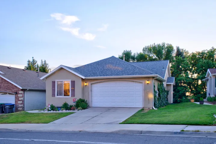Single-story residence featuring a two-car garage with a white door, a gray shingled roof, and a stucco exterior