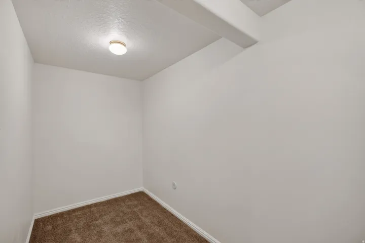 Compact interior space featuring light-colored walls and brown carpeting