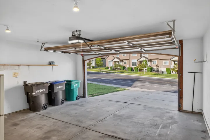 Attached garage featuring a concrete floor, white painted walls, and an automatic garage door opener