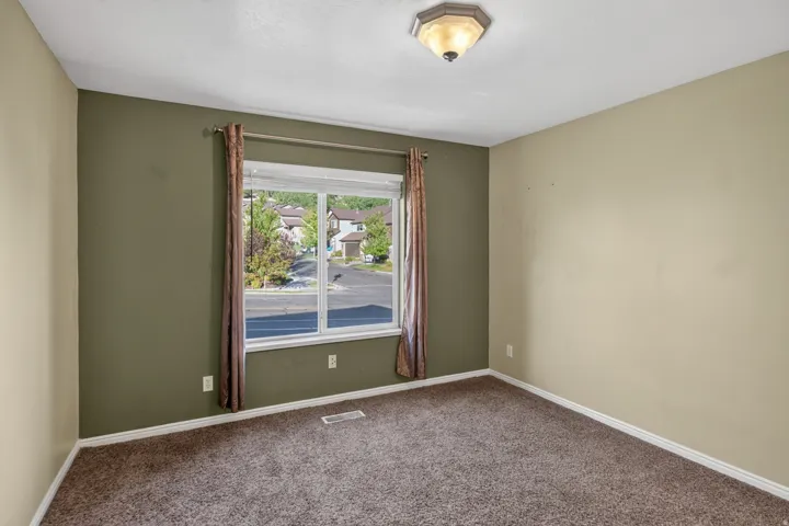 Interior room featuring neutral wall tones, a large window, brown carpet, and a ceiling-mounted light fixture