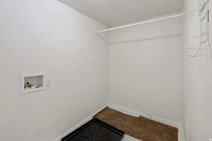 Dedicated utility space featuring washer and dryer connections, a white wire shelf, and wall-mounted storage racks