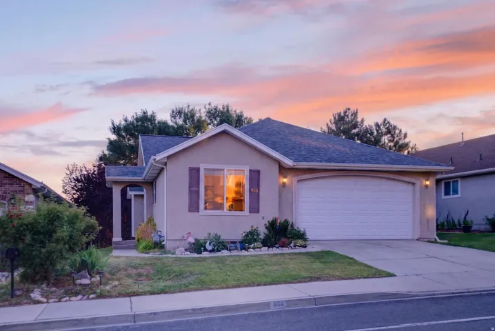 Stucco exterior featuring a two-car garage with an arched opening, a covered entryway, and a front yard with mature landscaping