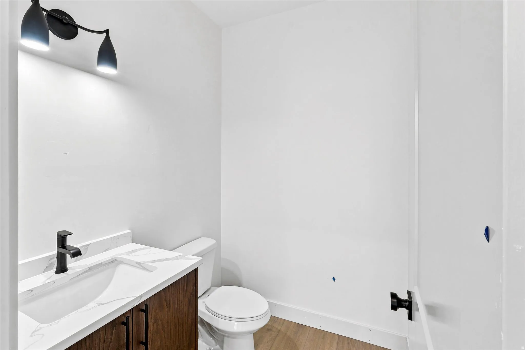 Modern vanity with a dark wood-finish cabinet, white countertop, and matte black faucet