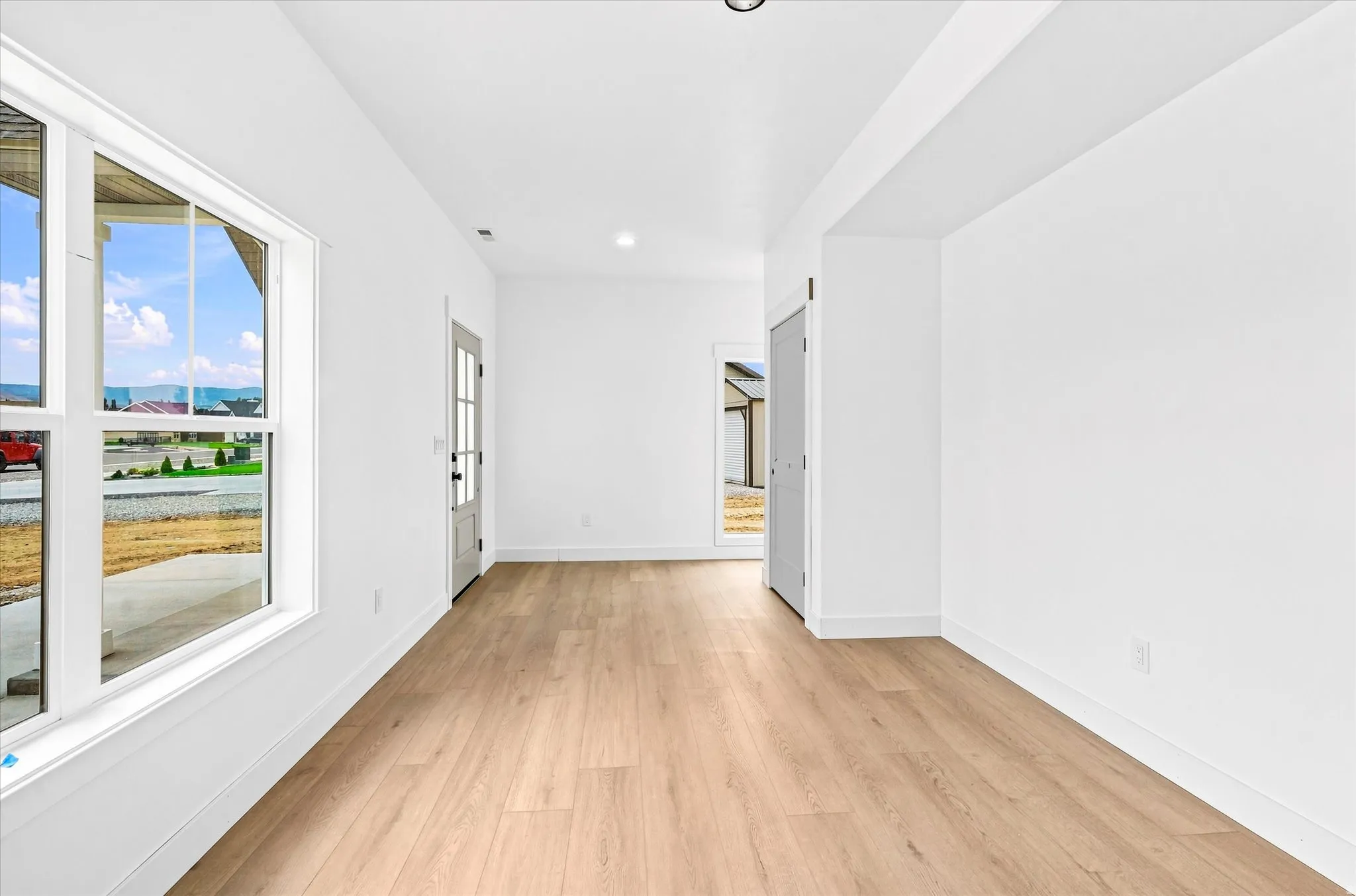 Recessed lighting, wood-finish flooring, white walls, white trim, and a glass-paneled entry door