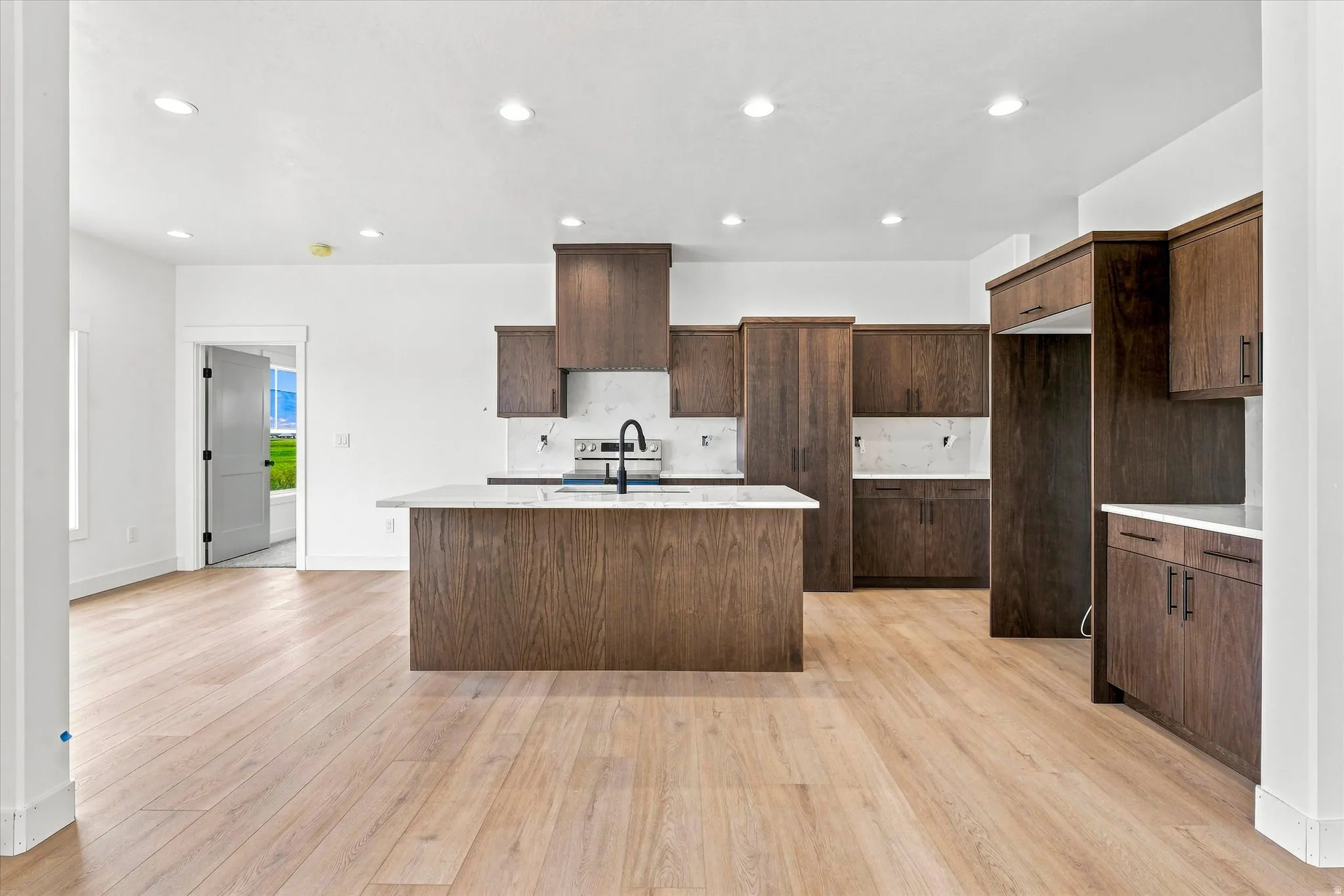 Spacious kitchen featuring wood-finish cabinetry, a central island with white countertop, and light wood-finish flooring