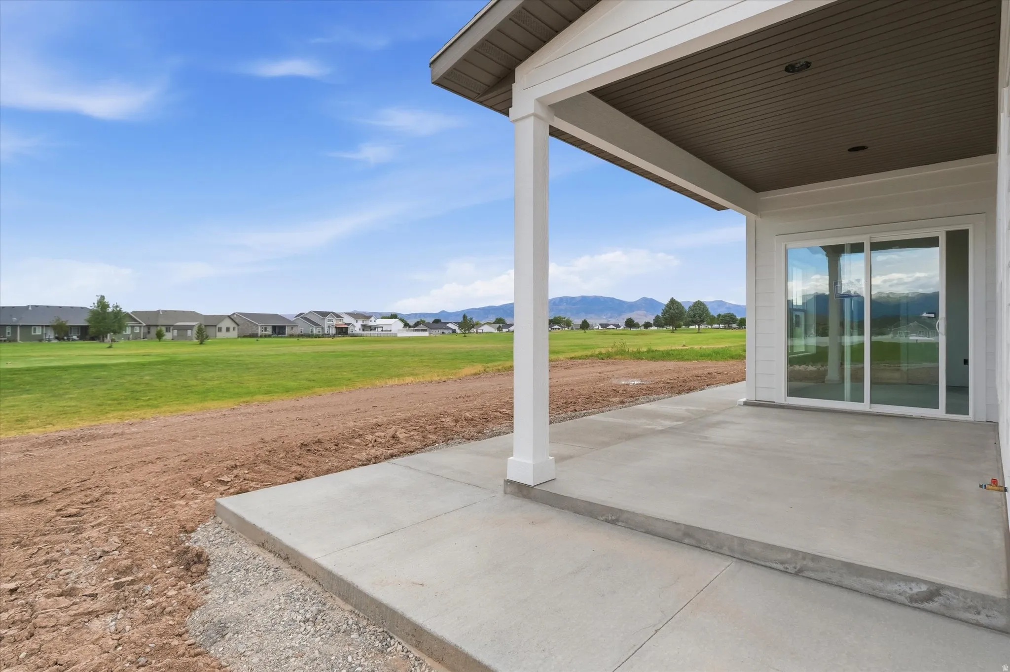 Covered patio with durable concrete flooring, white support columns, and a beadboard ceiling