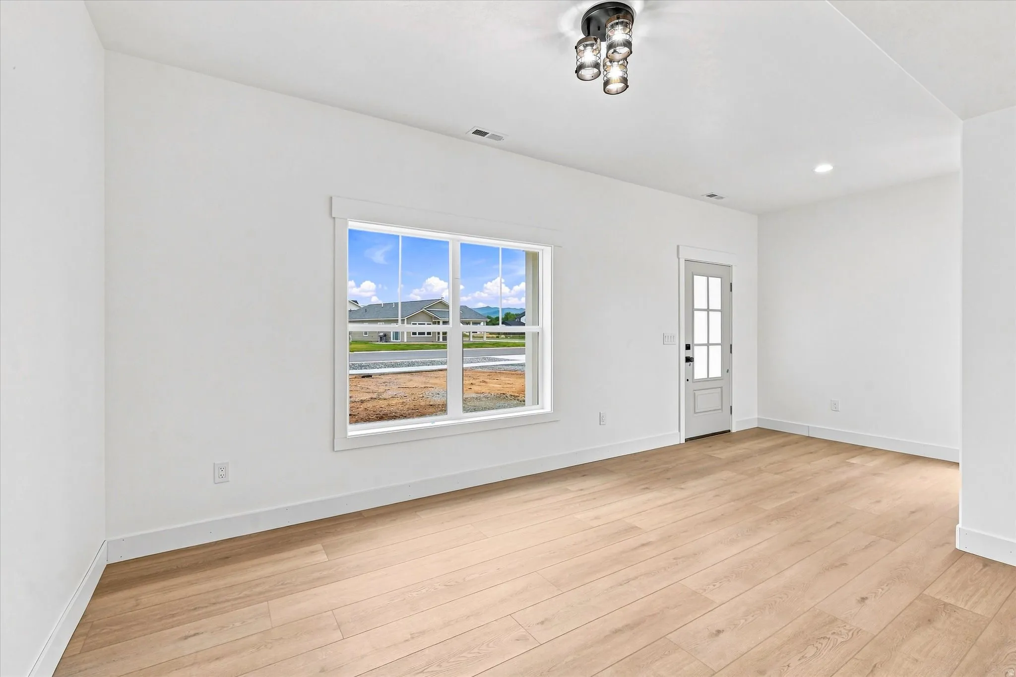 Wood-finish flooring, white trim, recessed lighting, and a multi-pane window