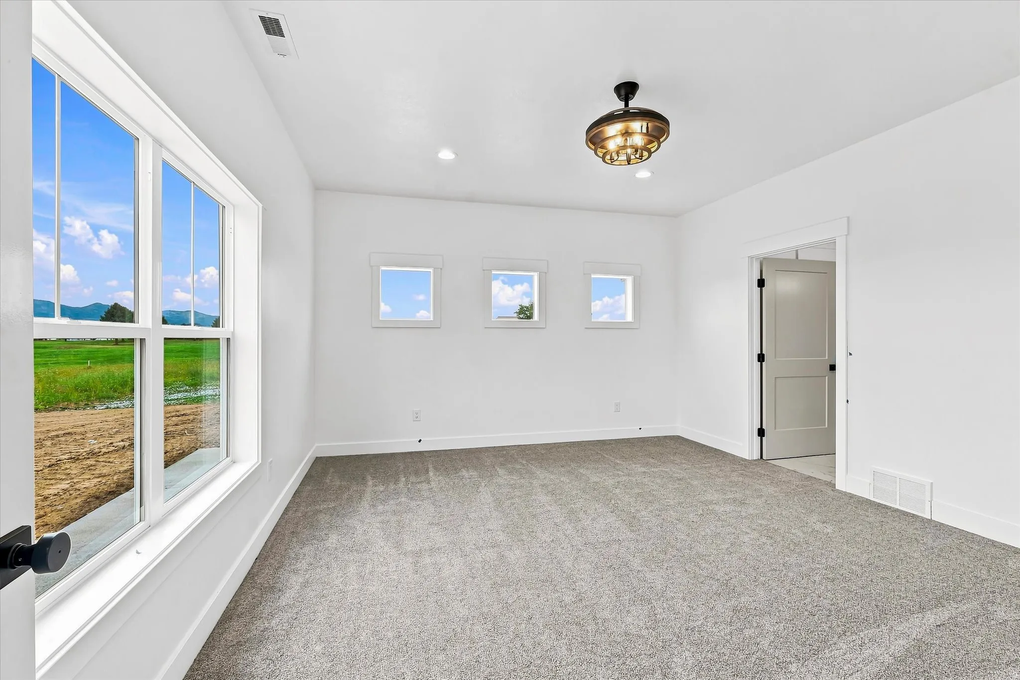 Spacious room featuring gray carpeting, recessed lighting, and a decorative ceiling fixture
