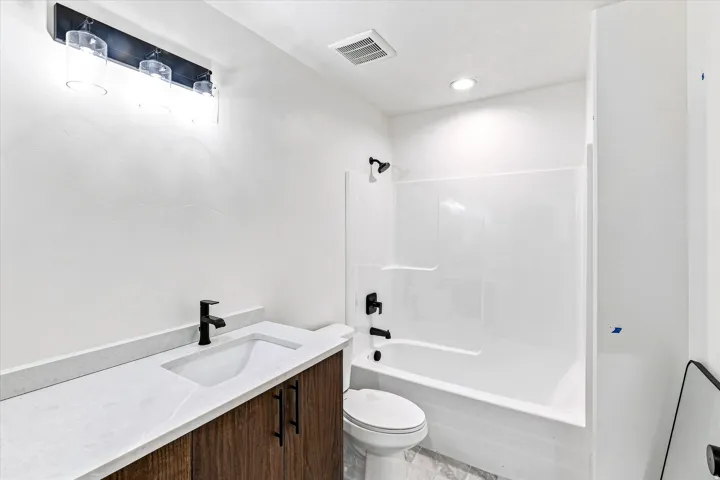 White vanity with a wood-finish base, integrated sink, and matte black faucet