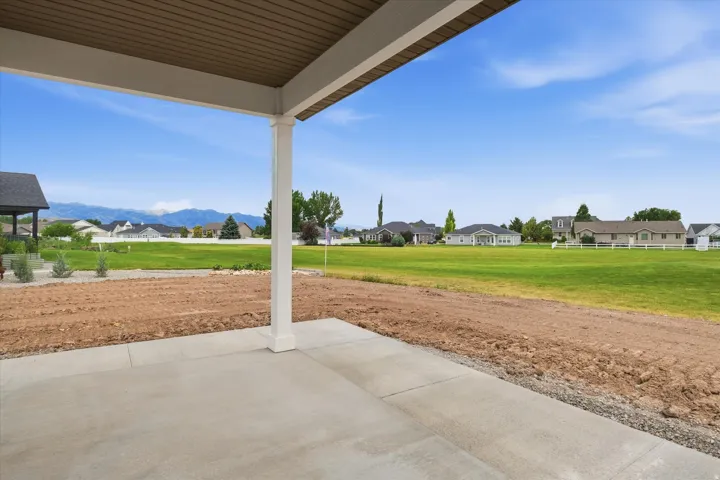 Covered patio featuring a concrete slab and white support columns, backs up to the green