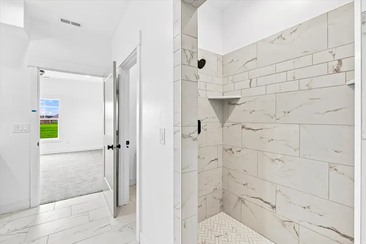Walk-in shower with tiled walls and a herringbone-patterned floor