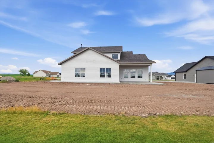Newly constructed home featuring white siding and a dark shingle roof